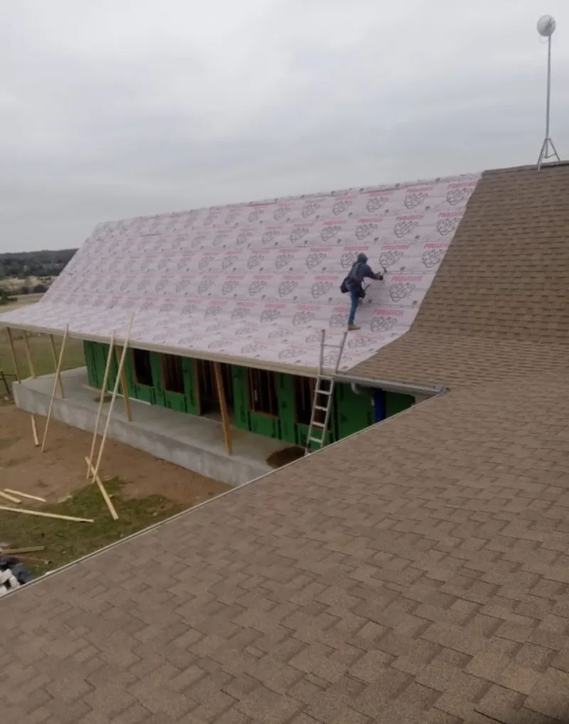 Worker preparing underlayment for a metal roof installation in Kaufman